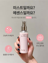 Person holding NOLA Collagen Skin Boosting Mist in pink bottle with text in Korean, highlighting the product's skin-enhancing benefits.